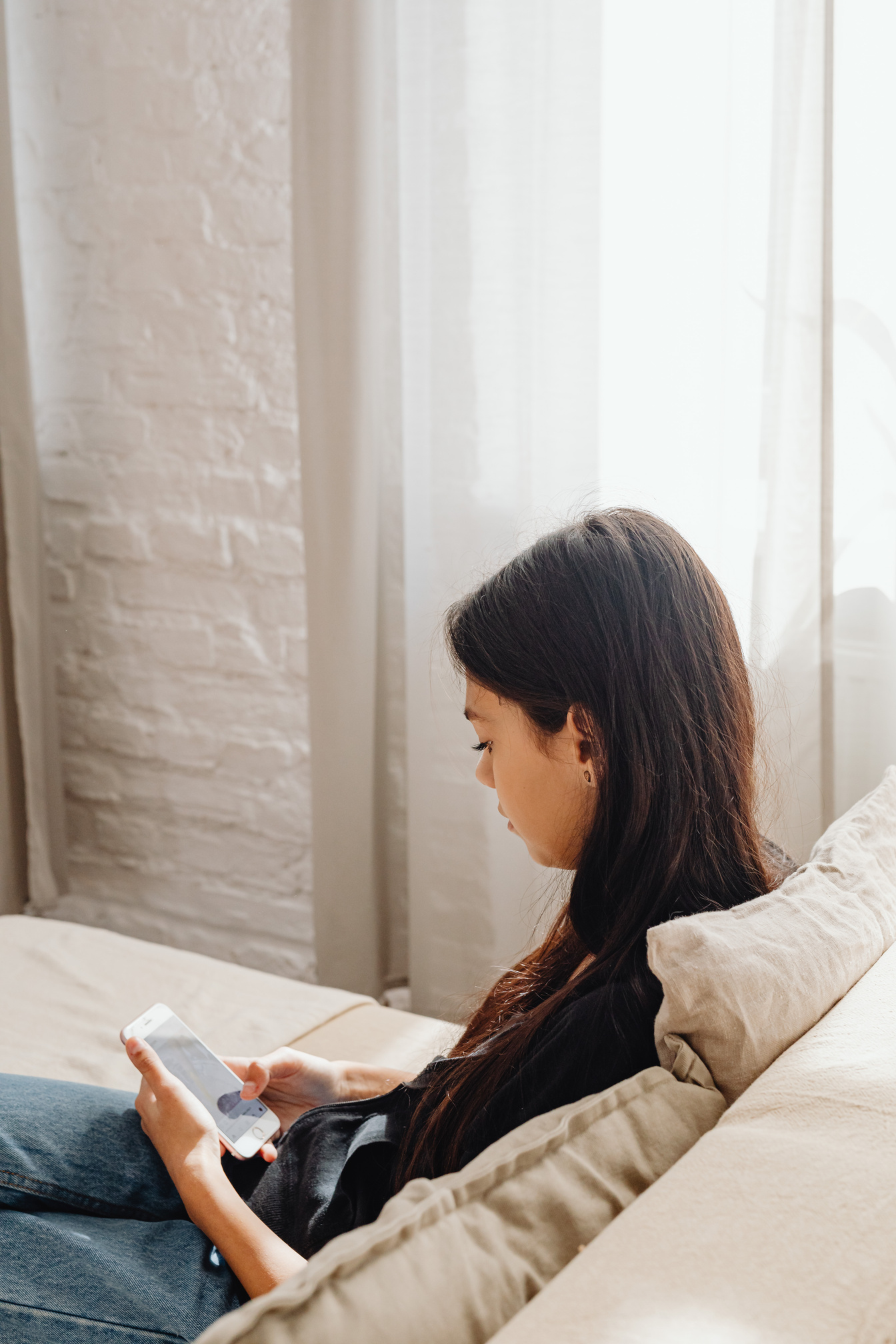 Woman Sitting on the Sofa Using a Smartphone